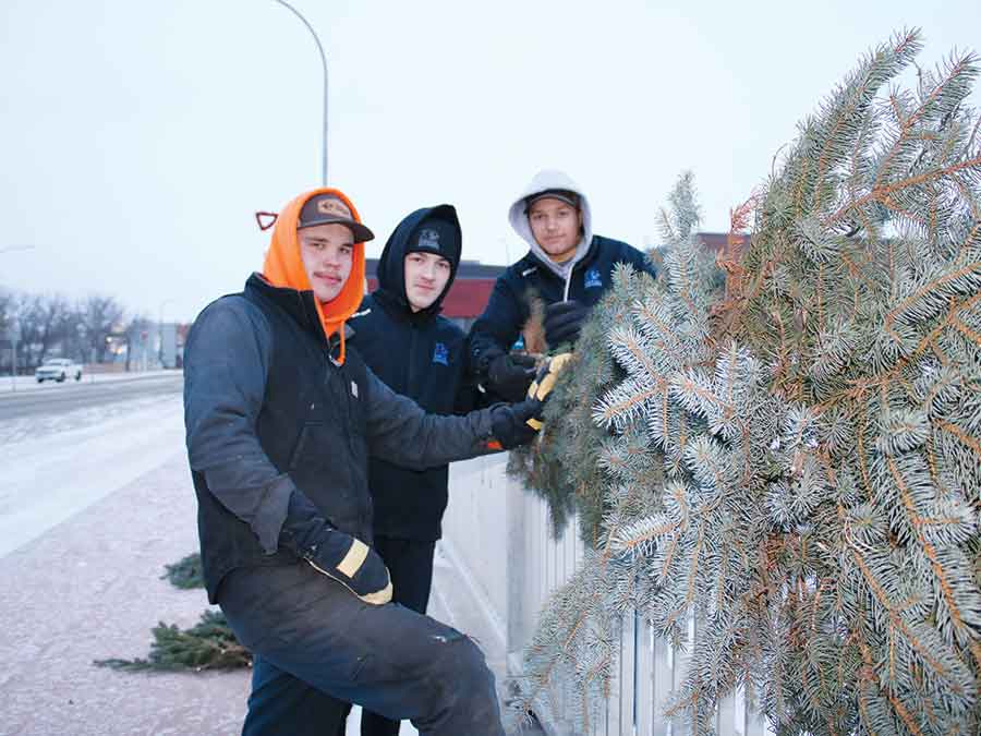 Carman Cougar Hockey members help hang pine on the Main Street Bridge for CIM