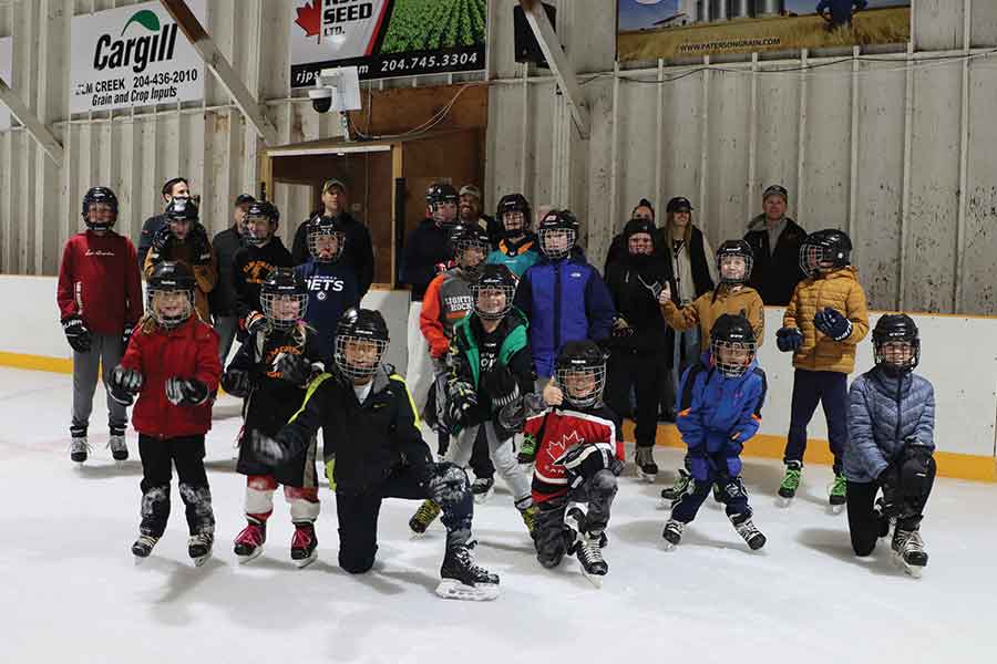 Community members gather on the new artificial ice for a group photo following the official ribbon-cutting ceremony at the Elm Creek Arena