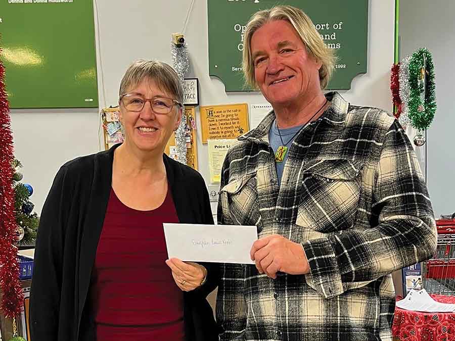 Evergreen Basic Needs executive director Karen Bowman accepts a $1,000 donation from Gimli Art Club president Don Fletcher to support the Christmas Hampers Program