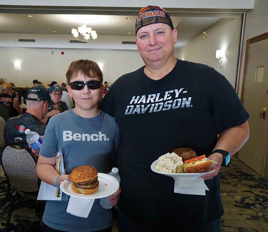 Scott Mullen and his 12-year-old son Jake enjoy a free burger during a lunch stop in Gimli as part of the Manitoba Motorcycle Ride for Dad on Saturday