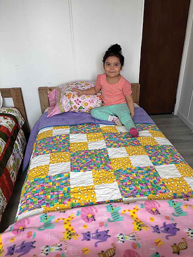 The kids are all smiles when they receive their new hand-built bed, completed with bedding and a comfy quilt