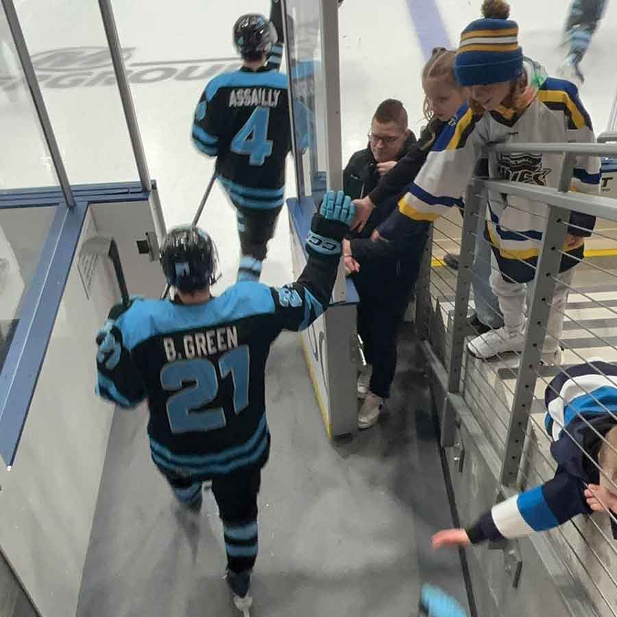 Wyatt Clarke and Quinn Cameron, another billet family, give high fives to Winnipeg Blues players as they take the ice ahead of MJHL action