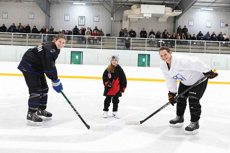 Blake Darragh (left) of the Wildcats lines up for the ceremonial puck drop with alumni player Stephanie Martens as Martens’ daughter, Emery — a U7 Teulon Tigers player — drops the puck