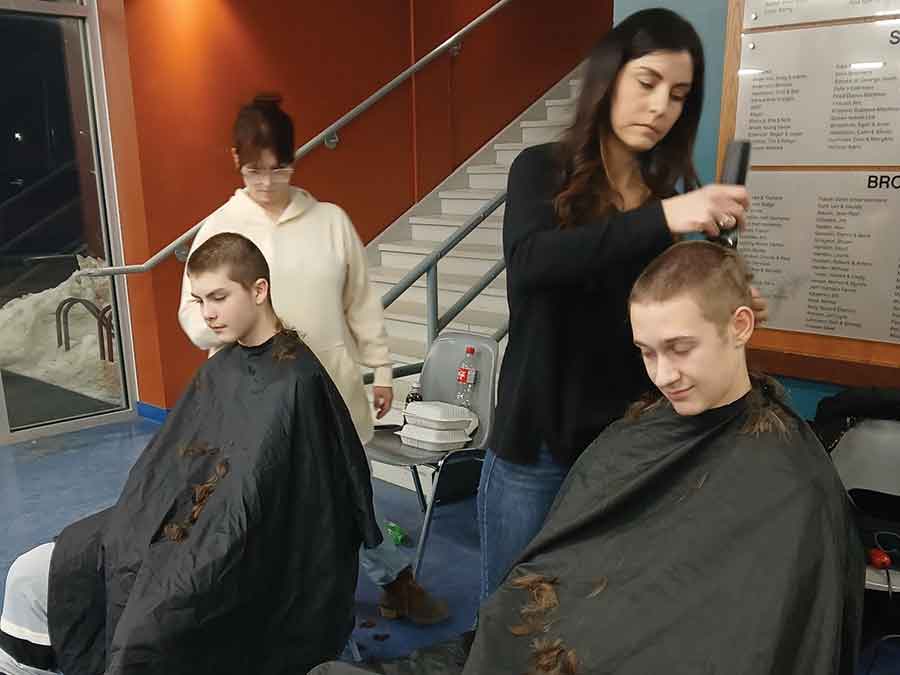 Marisa Wall of Essence Hair Salon (left) and Nicole Sabourin of Nicole’s Exquisite Styles cut hair of Twisters players, Justin Lavack and Sam Johnson