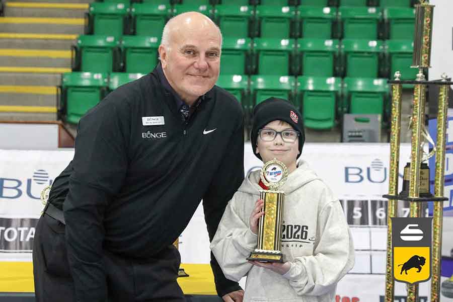Maddox Boaz, 9, with his second-place trophy he earned at the Hit, Draw, Tap Provincial Championships in Selkirk on Feb. 8. Pictured with Viterra representative Ray Baloun
