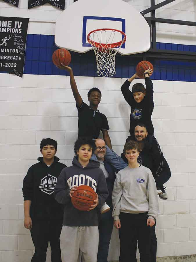Eric Smith, a longtime Carman basketball coach and volunteer, is leading a fundraising campaign to build a dedicated outdoor basketball court in Kings Park. Pictured with Smith are members of the junior varsity team. Front row (left to right): Sebastian Panganiban, Arkadii Anishchuk and Travis Knight. Back row (left to right): Bravin Tshondo and Sean Doell, with Jeff Knight, court committee member and junior varsity team assistant coach