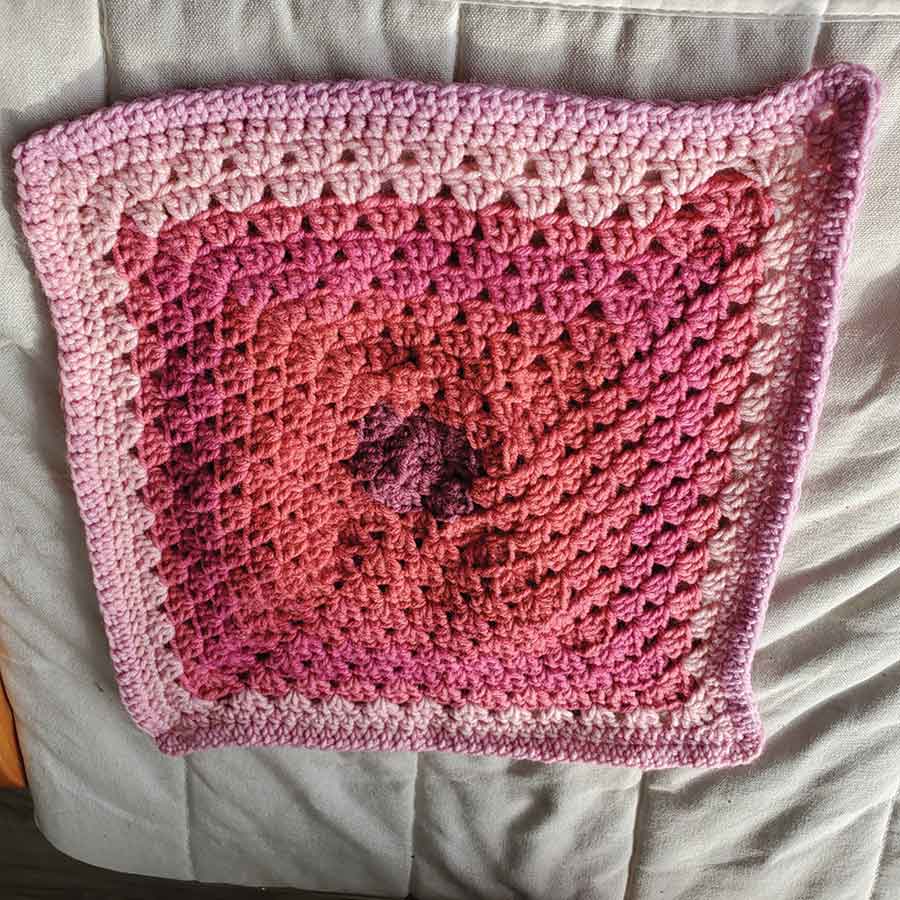 A completed 12-by-12-inch crochet square made from #4 worsted acrylic yarn