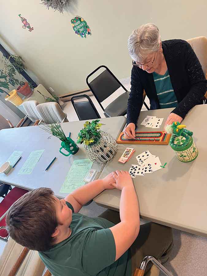 A Grade 4 student plays cribbage with his pen pal during their St. Patrick’s Day gathering