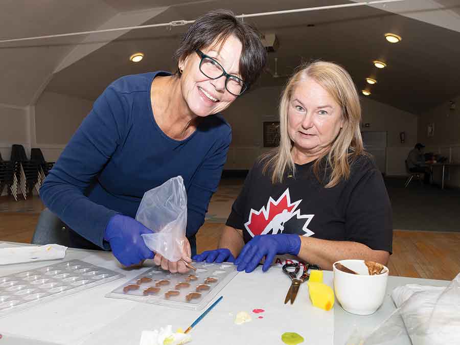 Kim Admiraal, left, and Alli Allec prepare chocolate bunnies to fill the smash eggs they created during an Easter smash egg workshop in Warren