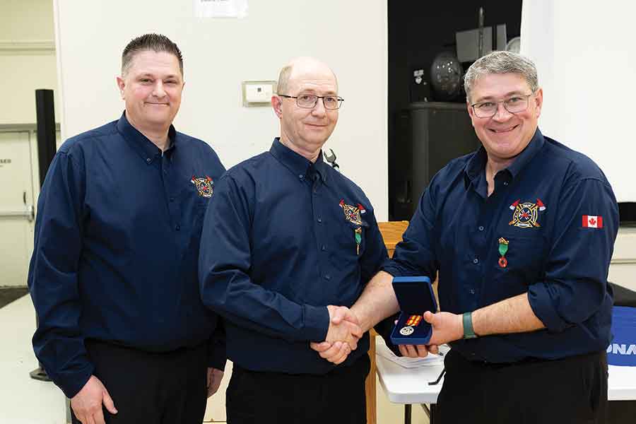 Danny Hutchinson (left) and Scott Skinner (right) presented Ryan Trombo with a Manitoba Fire Services Exemplary Service medal