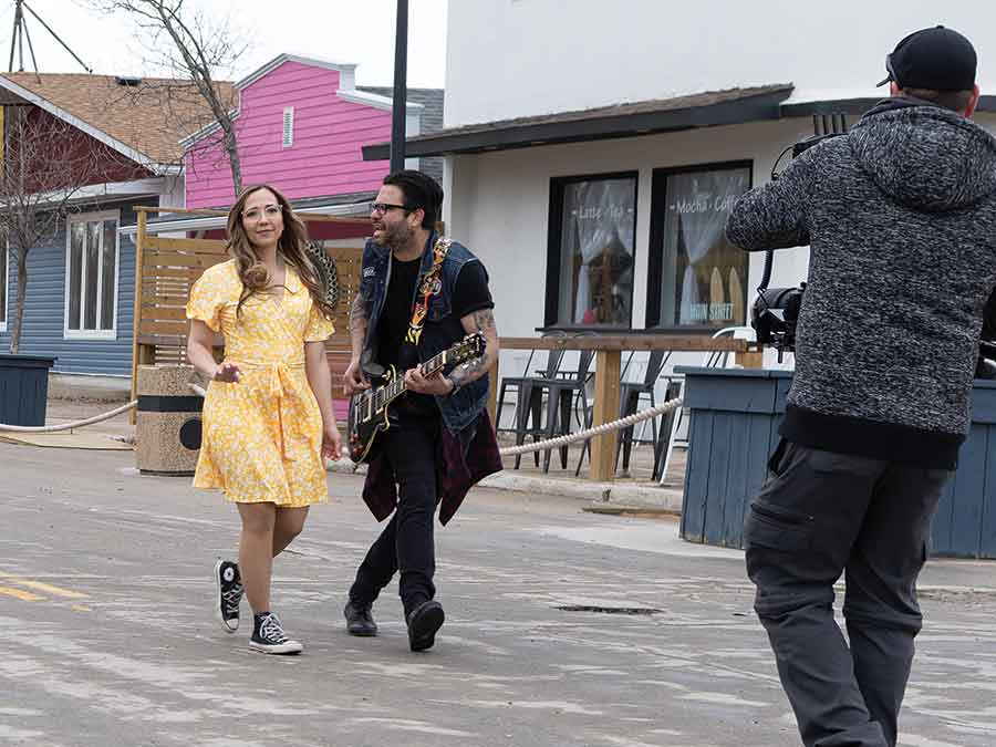 The lead singer of The Bloodshots belts out the lyrics to “Gettin’ Around” to a model on Main Street in Winnipeg Beach while being filmed by Trav Anema on May 16