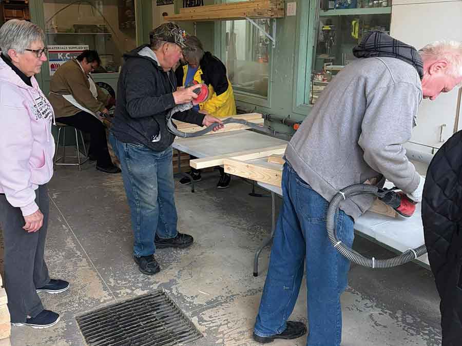 Volunteers Donna Grainger, Thor Stevens and Conrad Reimer assemble headboards