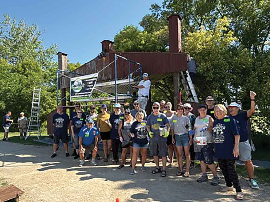 Professional painter John Torfason applies a fresh coat of stain to the iconic Winnipeg Beach Boardwalk sign on June 26 as nearly 30 volunteers came together to restore the landmark ahead of Canada Day. The community-led project transformed one of the town’s most recognizable welcome signs through a day of teamwork and volunteer effort